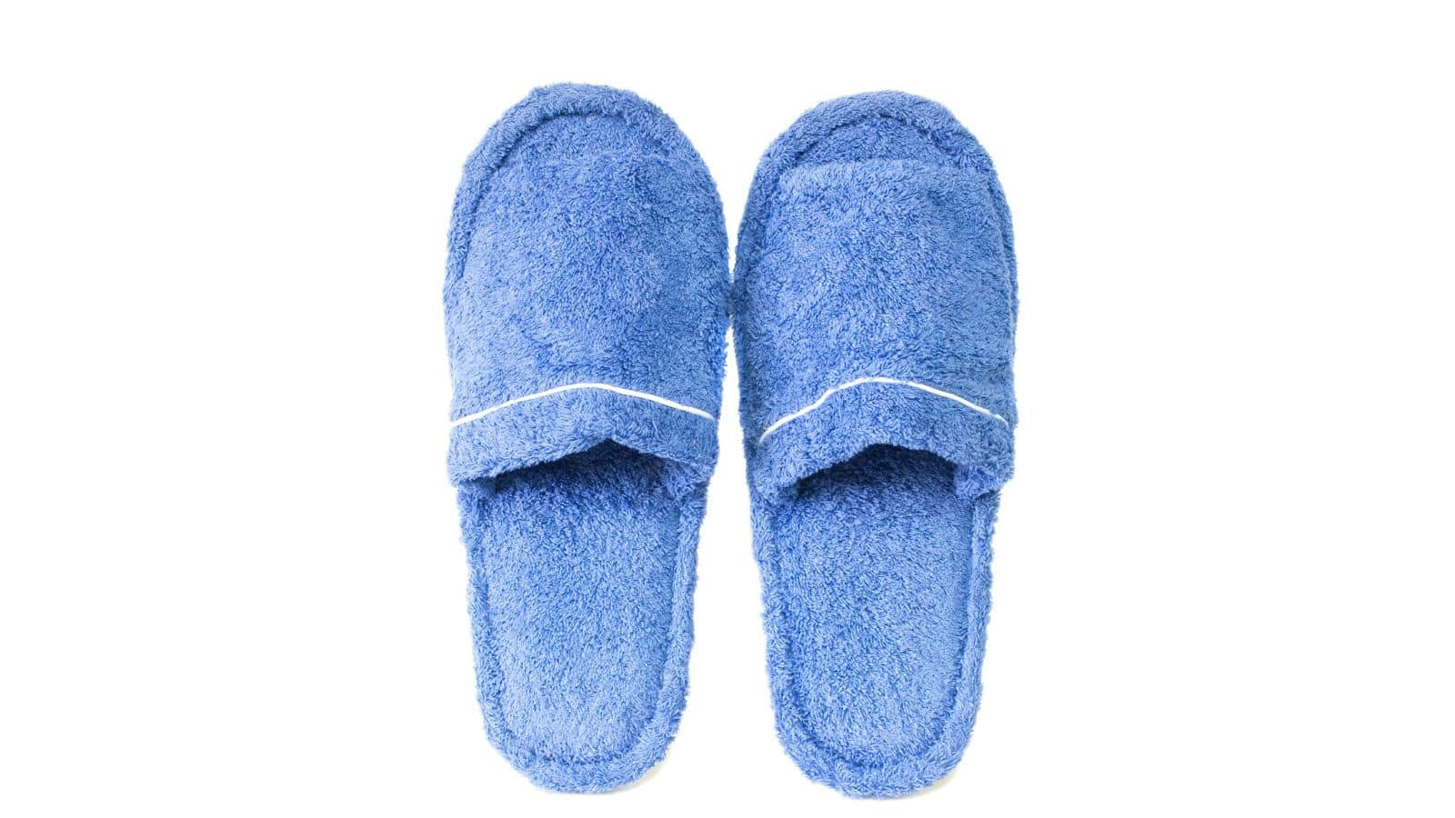 A pair of blue fuzzy slippers is placed side by side on a white background.
