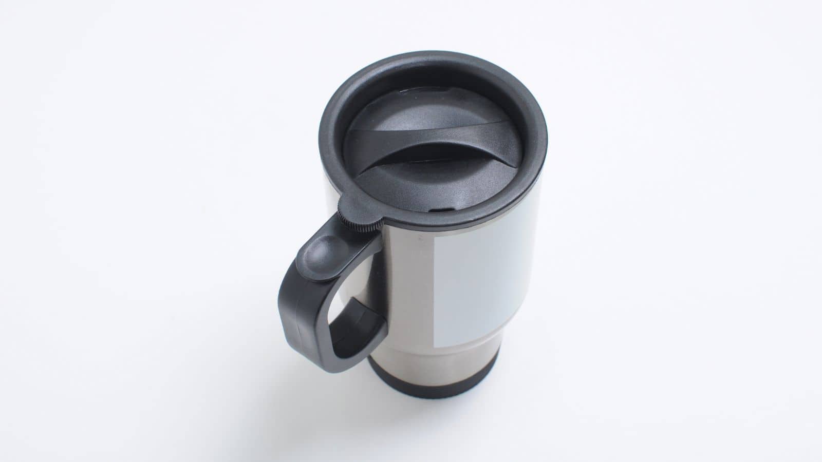 A stainless steel travel mug with a black plastic lid and handle is seen from a high angle on a white background. The lid is closed, and the mug appears to be designed for hot beverages.