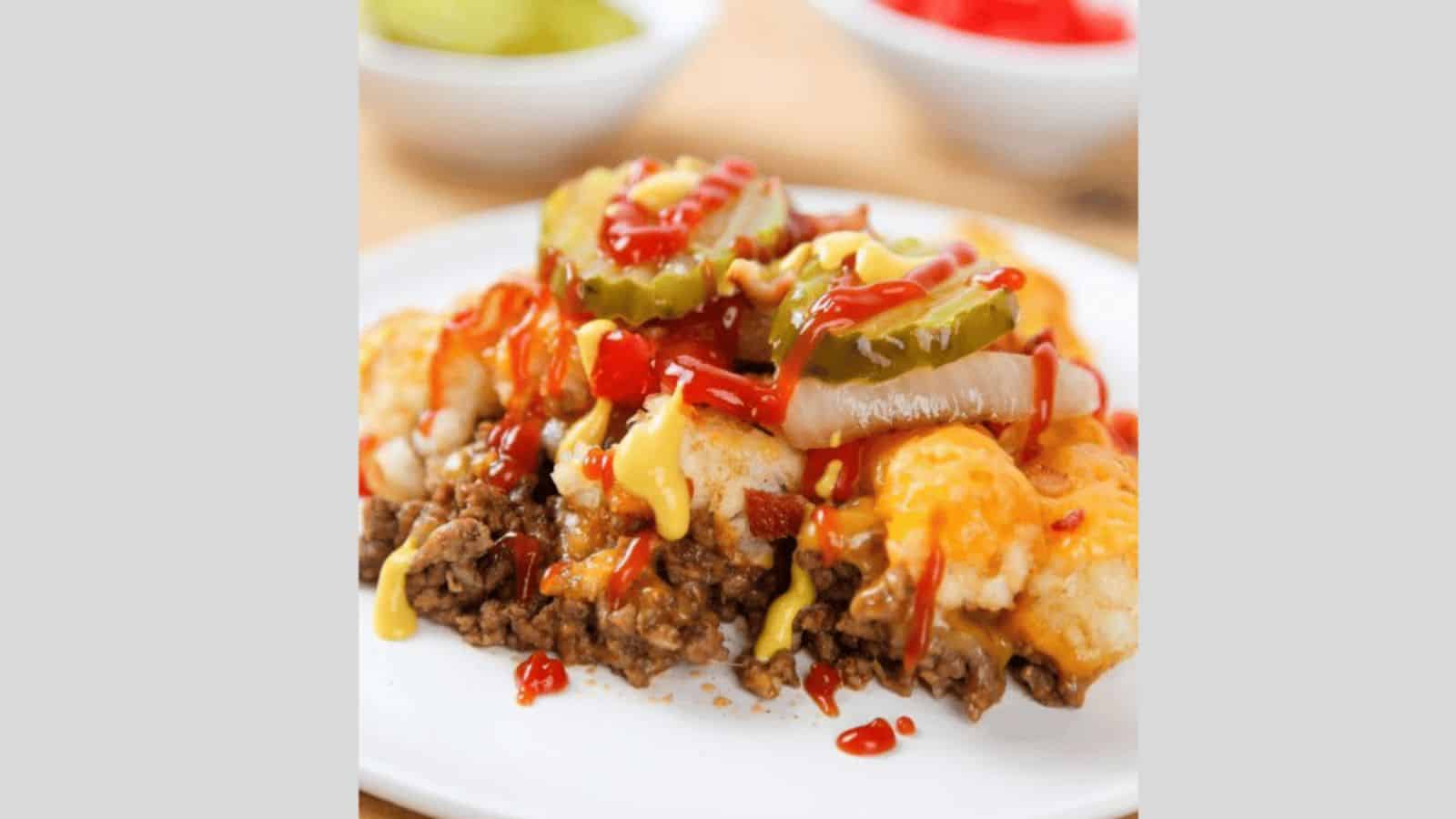 A top-down shot of Cheeseburger Casserole with pickles and cheese nearby.