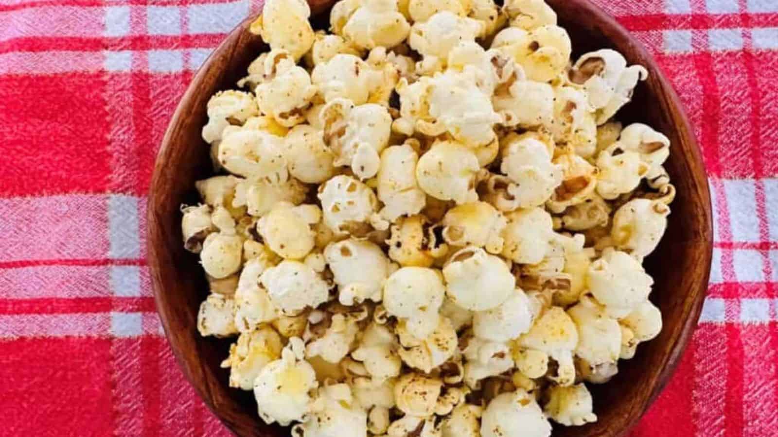 A bowl of popcorn on a red and white checkered tablecloth.