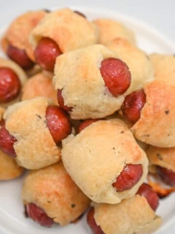 Hot dog buns with little smokies on a plate.