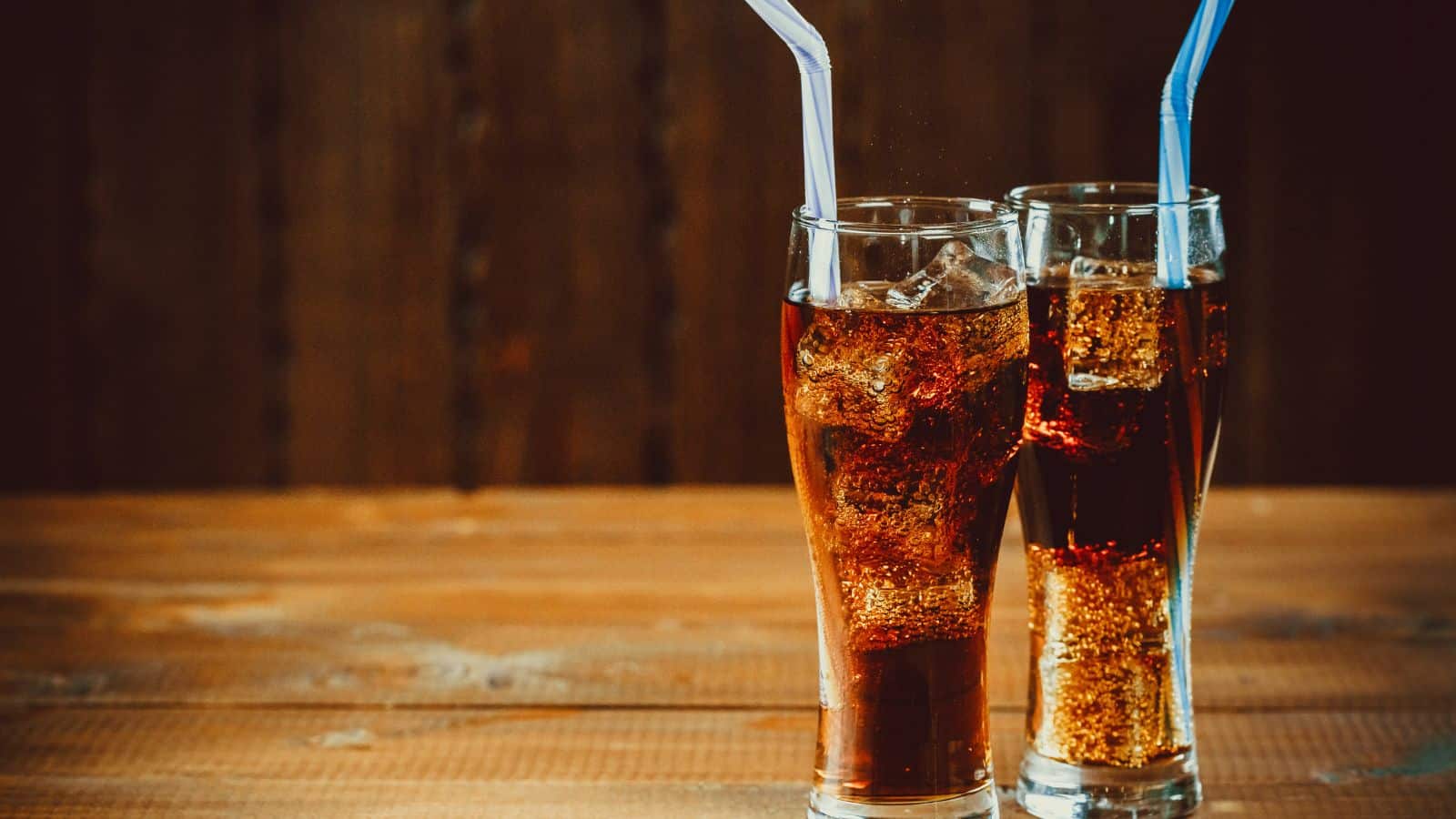 Two glasses of carbonated soft drinks with colored straws.