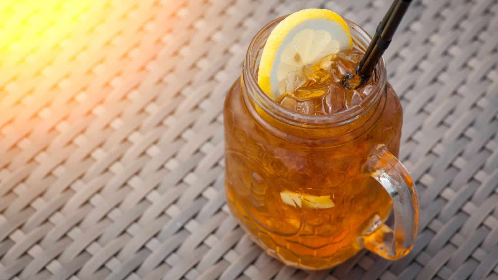 A glass of lemon iced tea with a slice of lemon as garnish.
