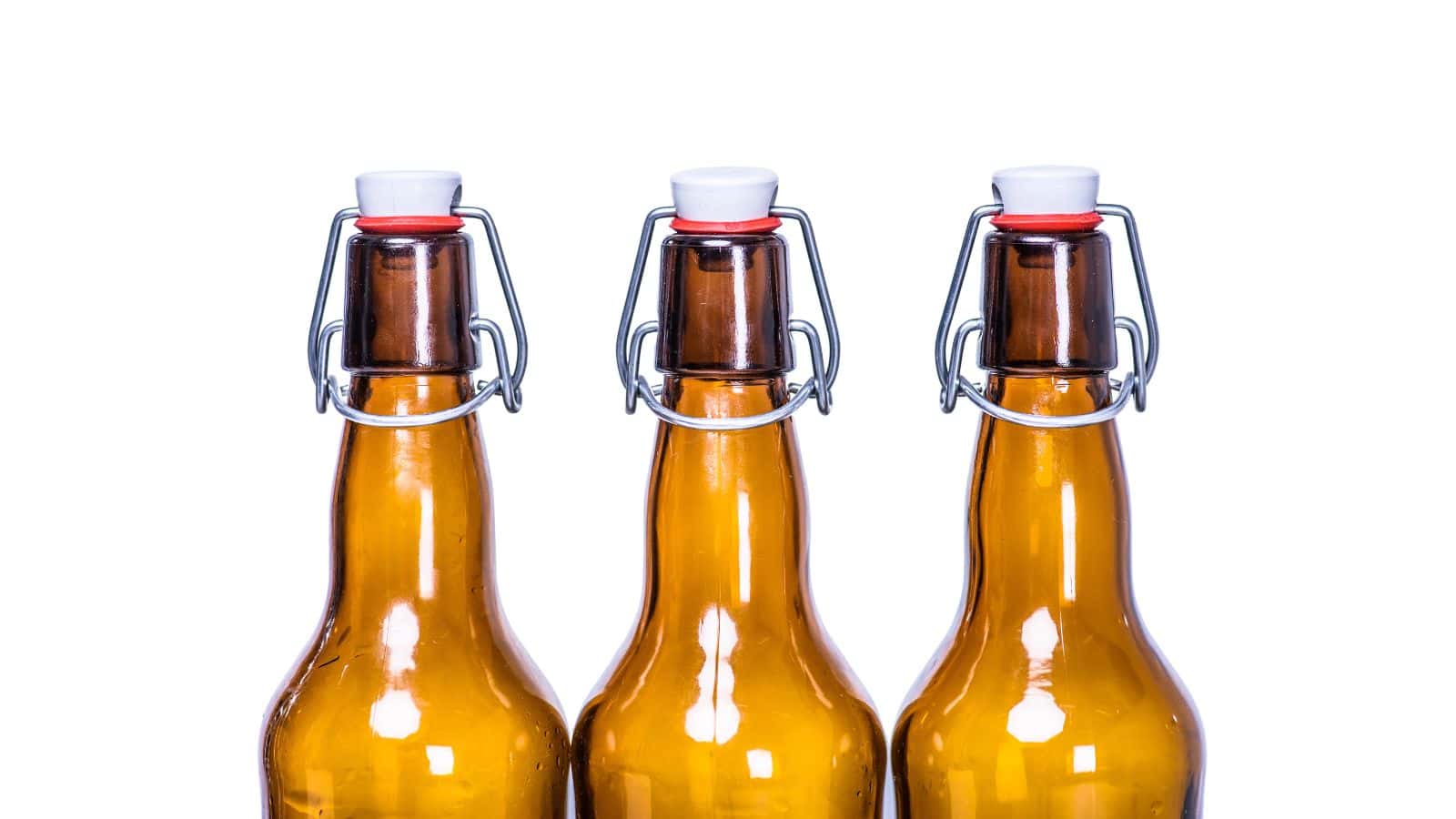 Three brown glass bottles with metal swing-top caps are aligned side by side against a white background. The bottles have a flip-top mechanism and white stoppers with red rubber seals.