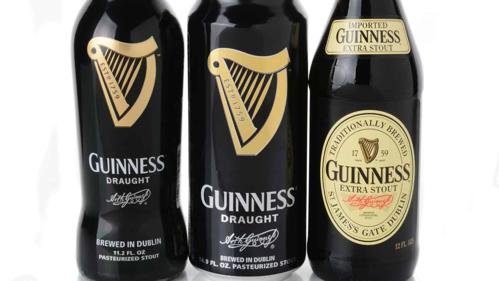 Three bottles of Guinness are shown: two are Guinness Draught in black cans, and one is Guinness Extra Stout in a glass bottle. All items feature the distinctive Guinness harp logo on their labels.
