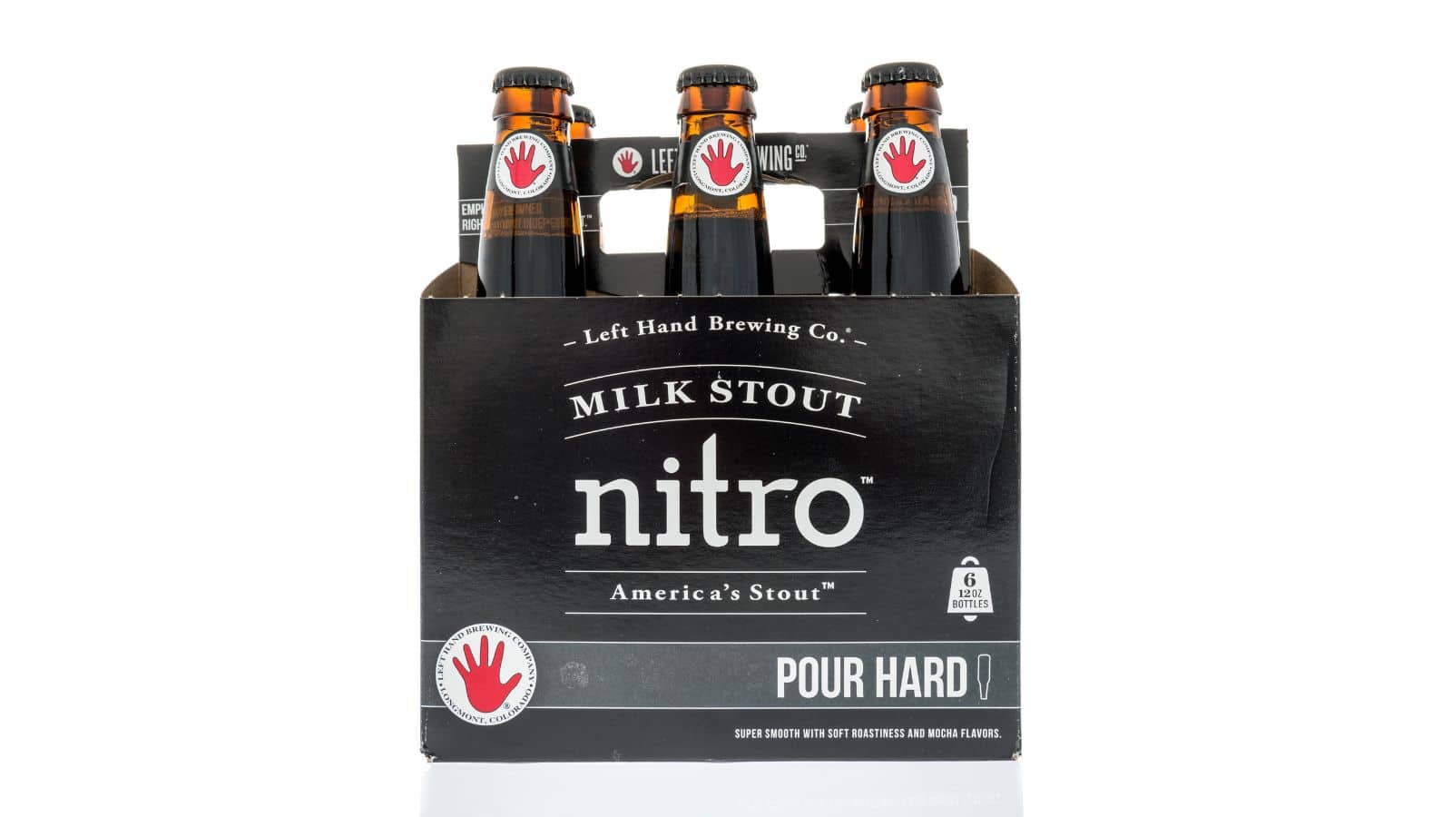 A six-pack of bottles labeled "Left Hand Brewing Co." with "Milk Stout Nitro" prominently displayed. The packaging is black with white and red text, featuring a red hand logo. The text advises to "Pour Hard.
