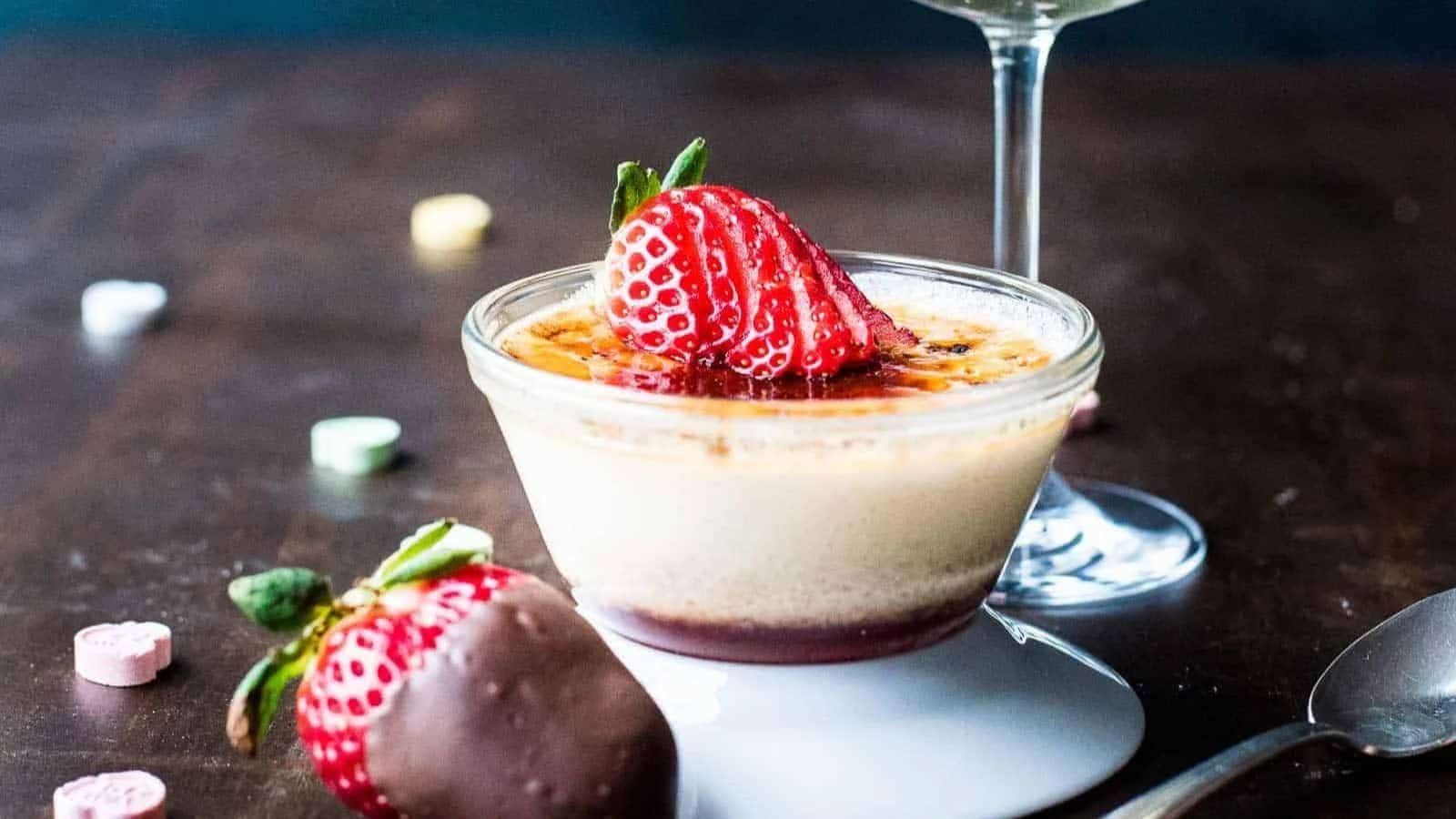 Close up of strawberry cr&egrave;me br&ucirc;l&eacute;e next to a glass of champagne.