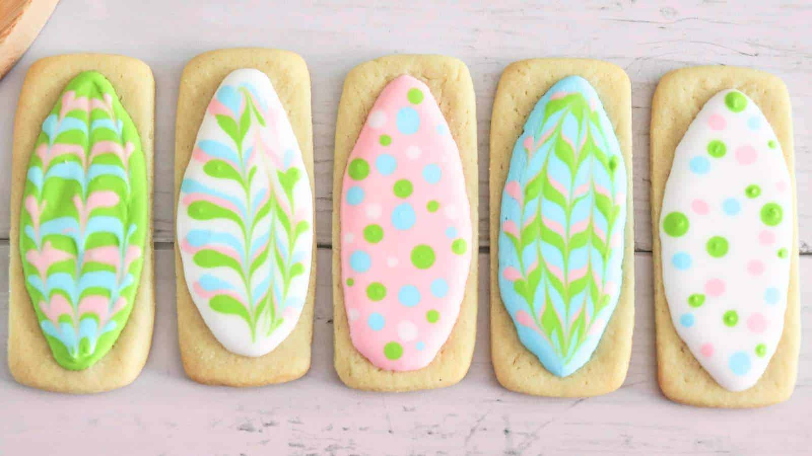 A row of easter egg-shaped cookies with colorful icing designs on a light wooden surface.
