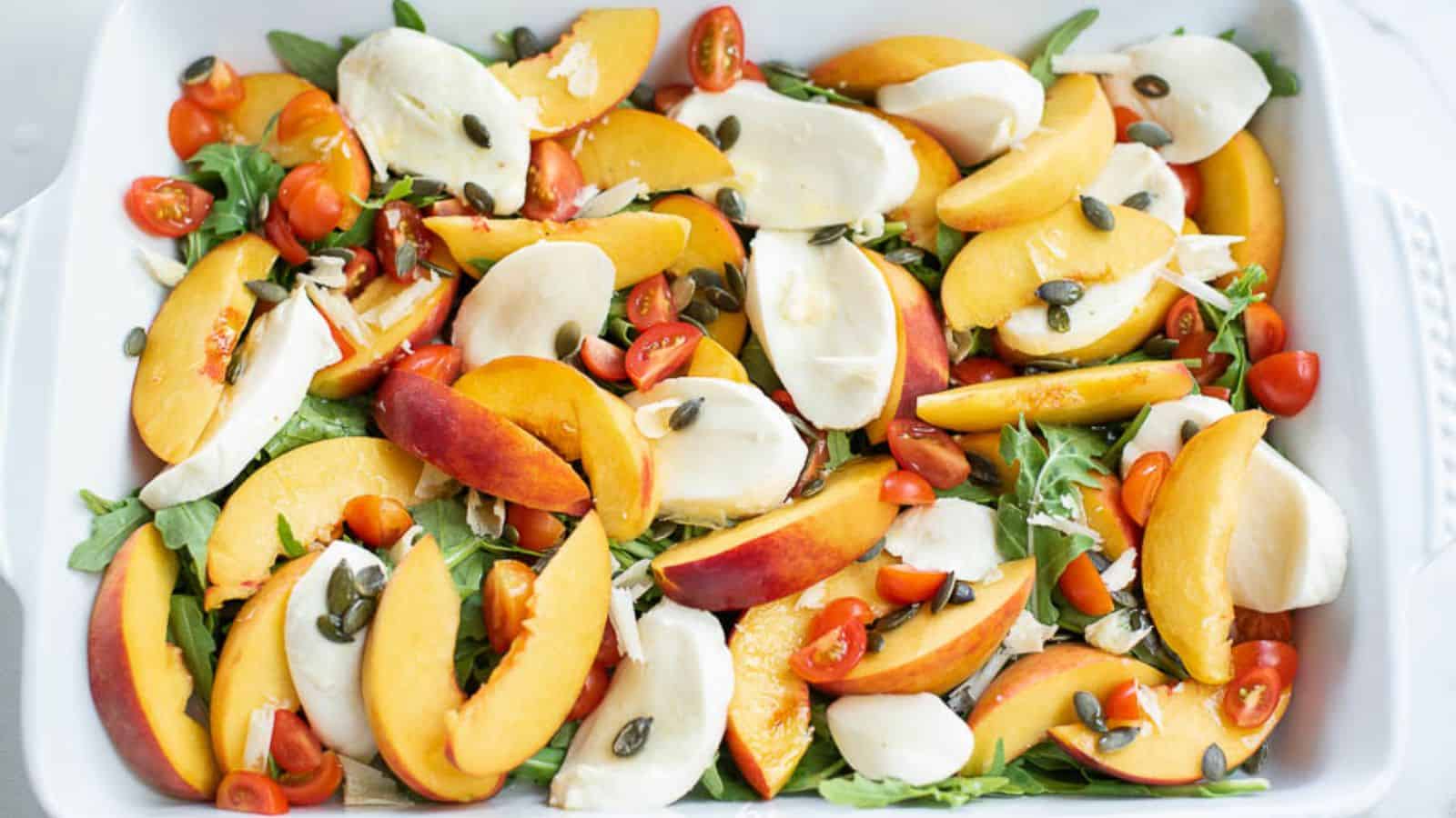 Sliced peaches, tomatoes, and fresh mozzarella slices on a tray.