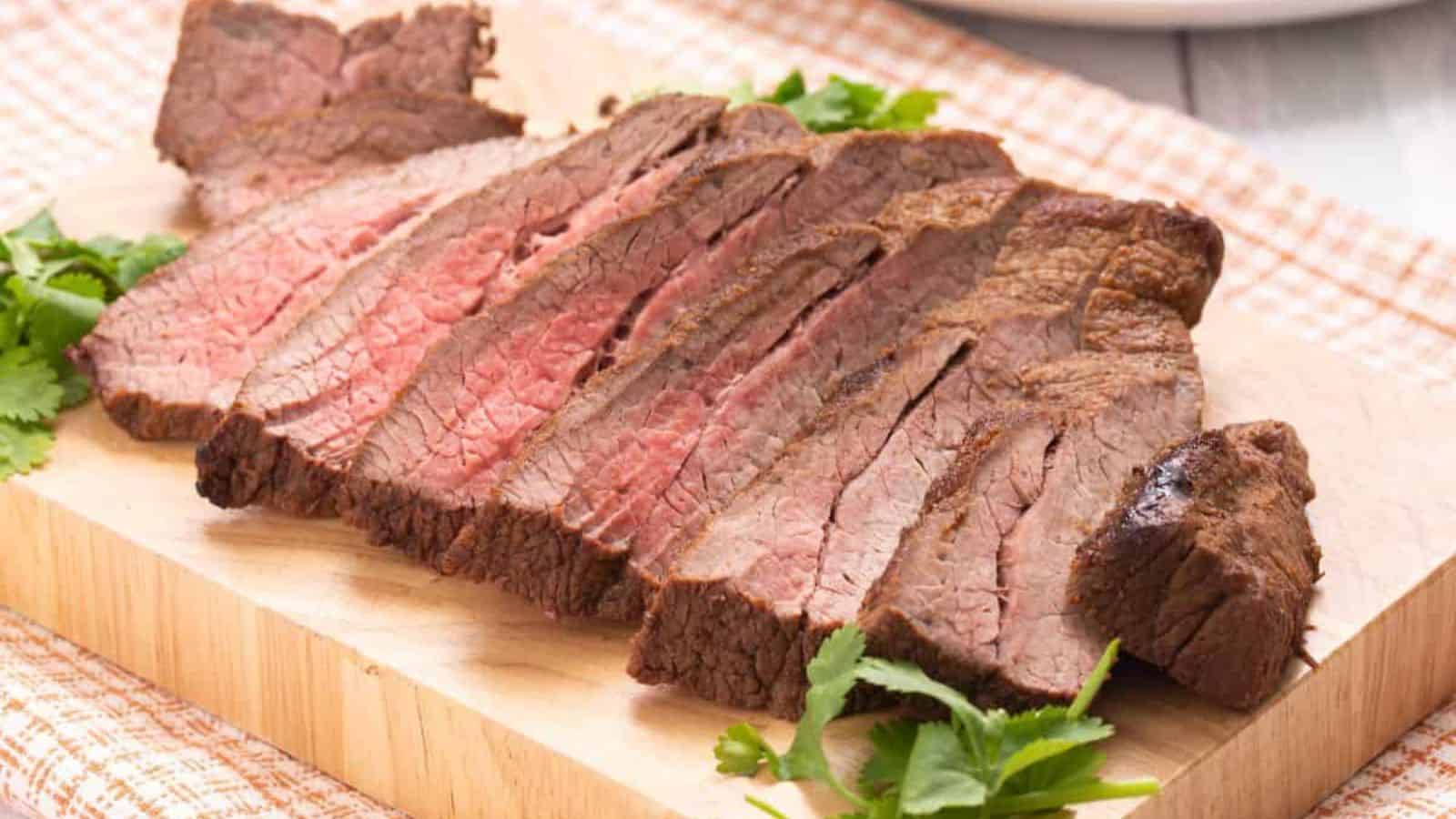 Slices of baked carne asada on small wood cutting board.