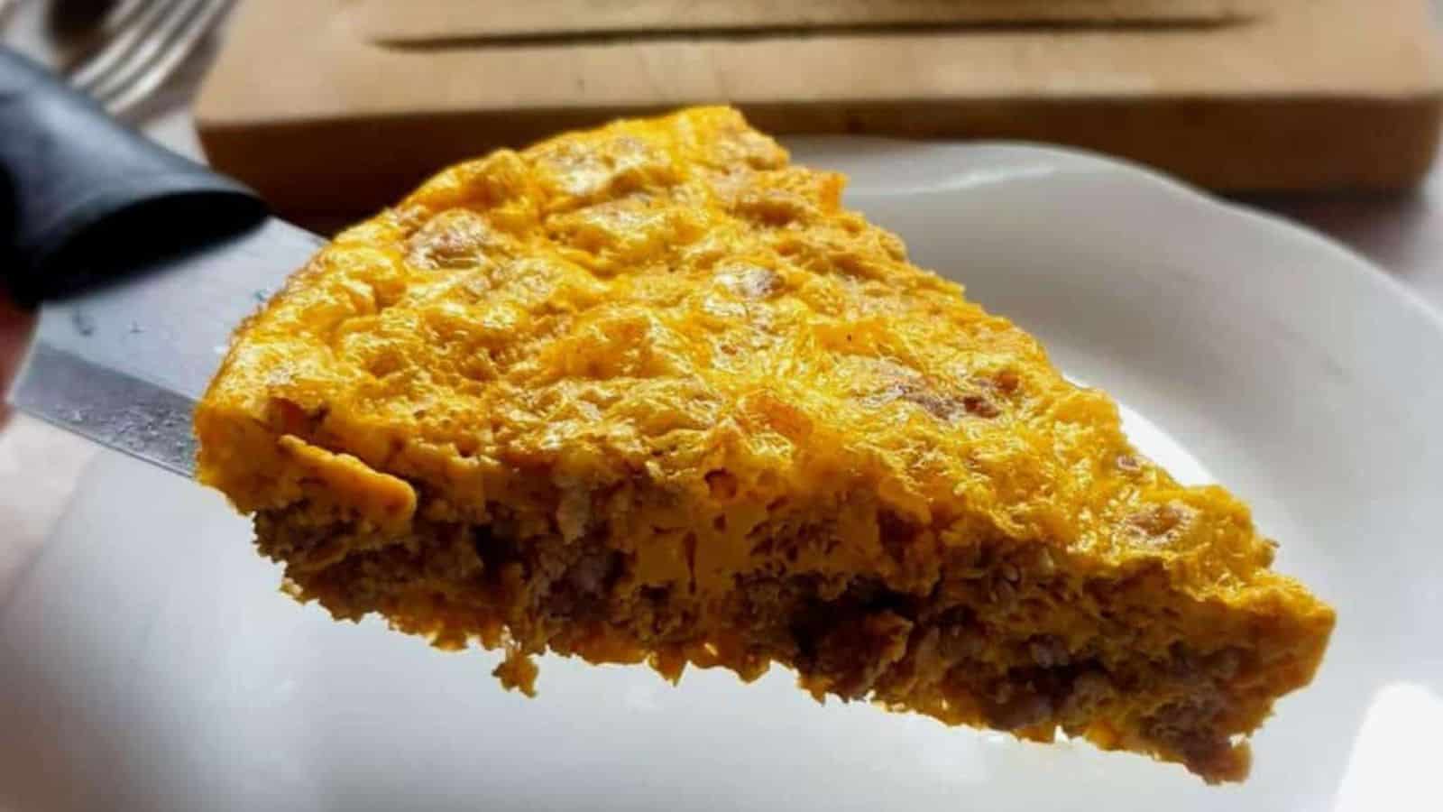 A person cutting a piece out of a casserole.