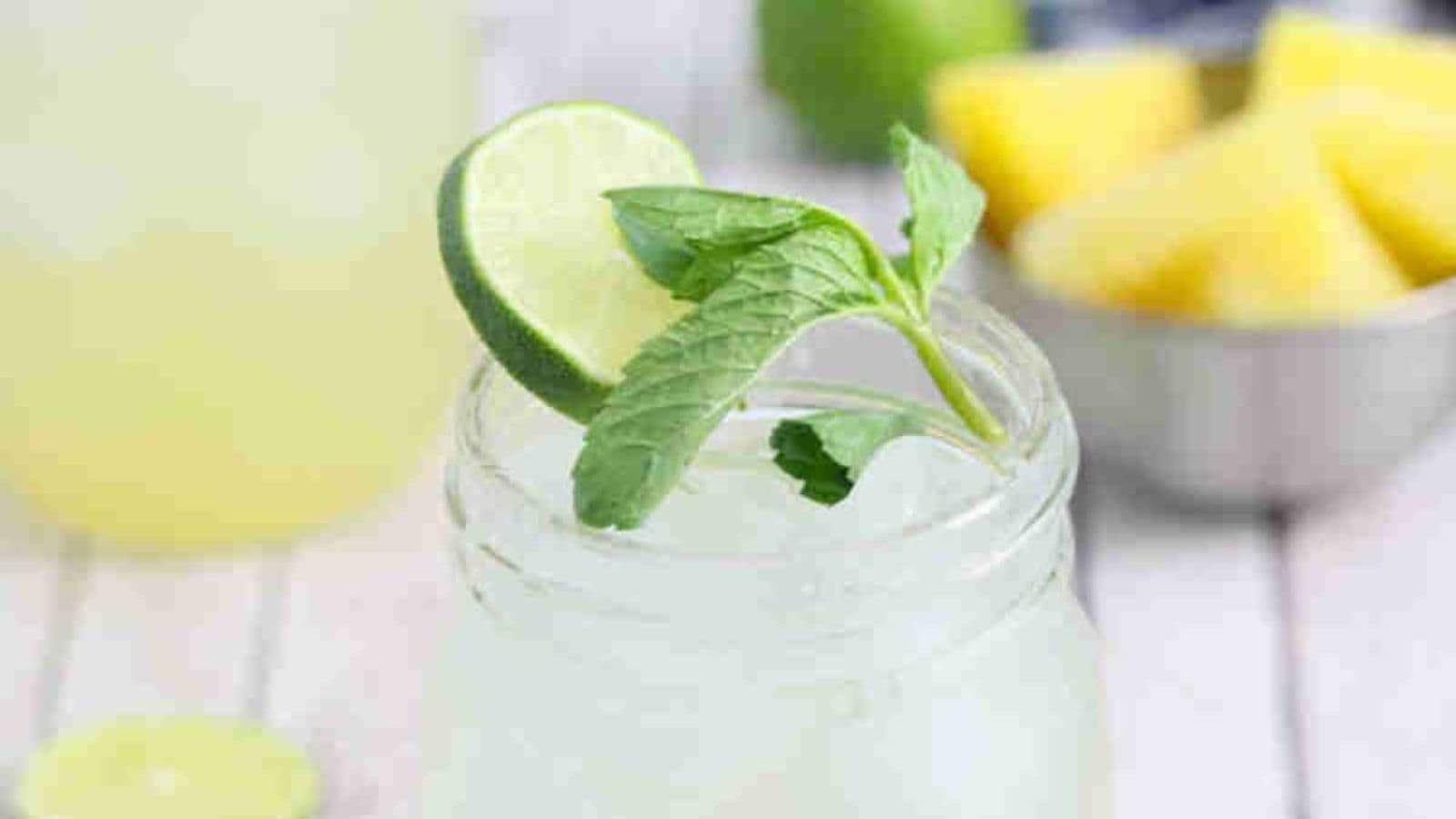 Ginger beer mocktail in a mason jar with fresh mint and lime on the jar and ingredients and another jar around it.