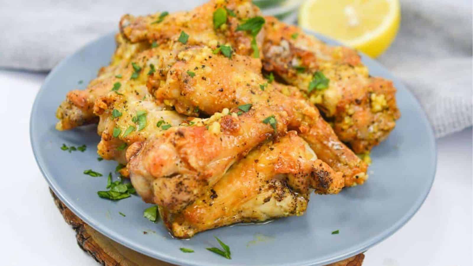 Chicken wings on a plate with lemon wedges.