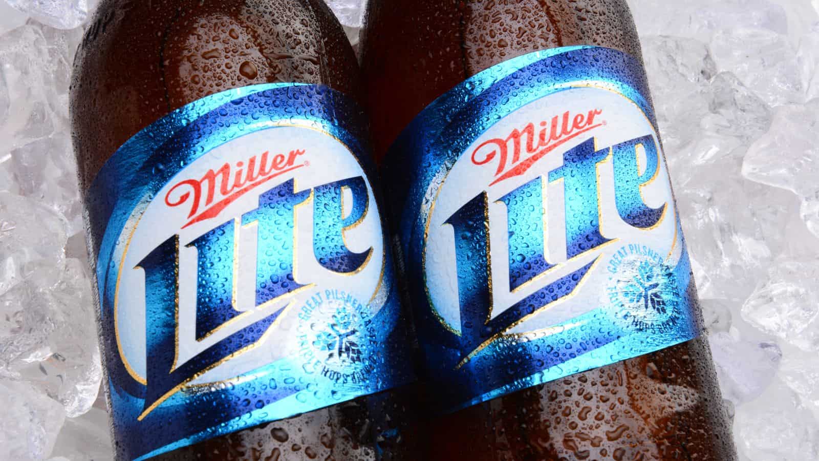 Two bottles of Miller Lite beer with condensation on them are lying on ice. The blue and white labels with the words “Miller Lite” are clearly visible.