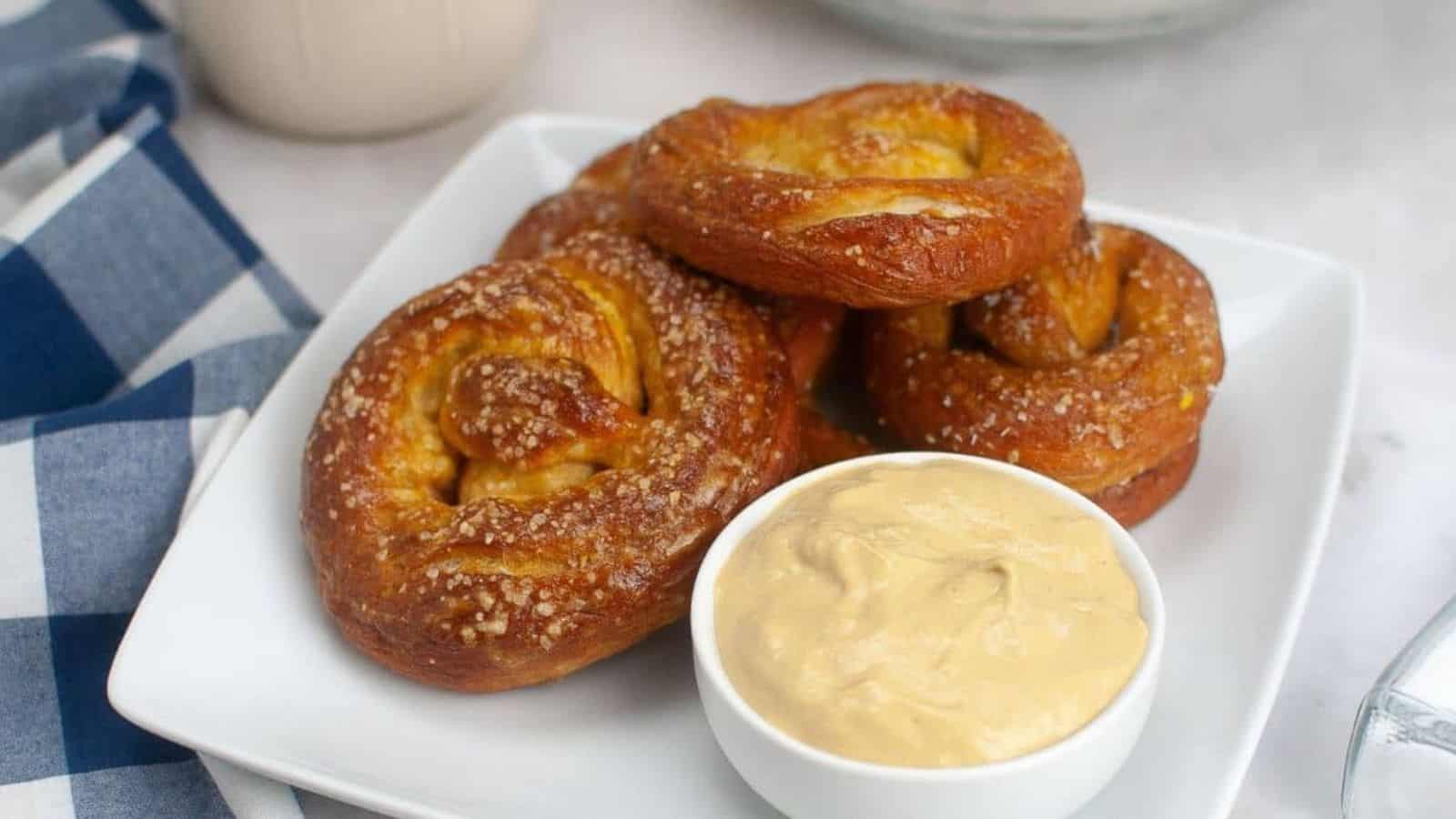 Five sourdough soft pretzels stacked on a plate.