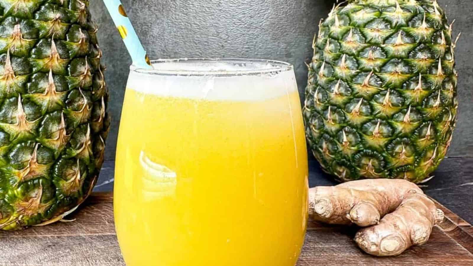 Refreshing and healthy juice made with sweet pineapple and spicy ginger in a glass with a blue color straw.