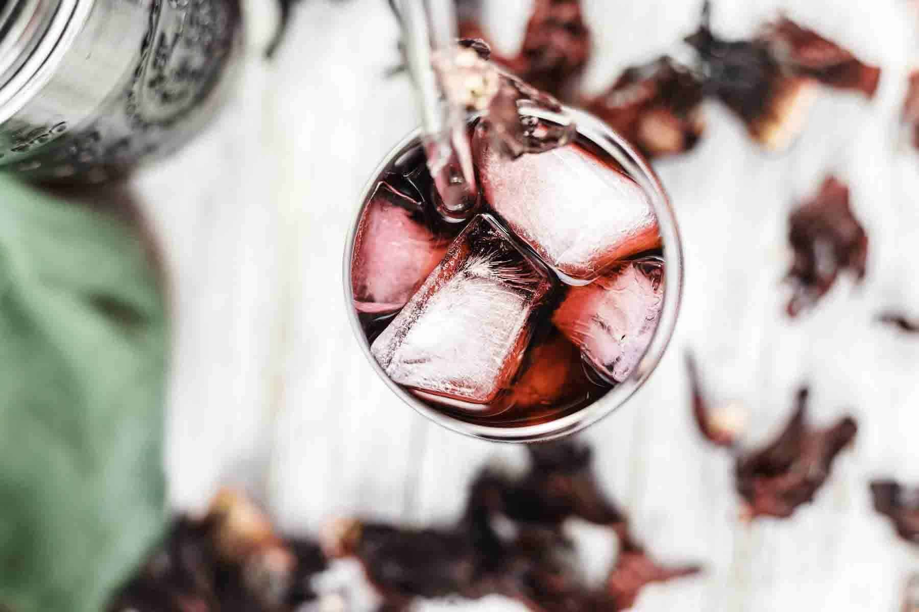 A top view of a glass filled with ice cubes and a Karkade Tea.