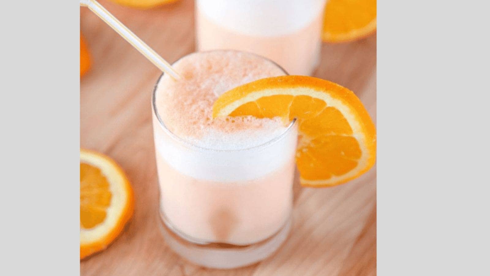 Two orange julius drinks garnished with an orange wedge.