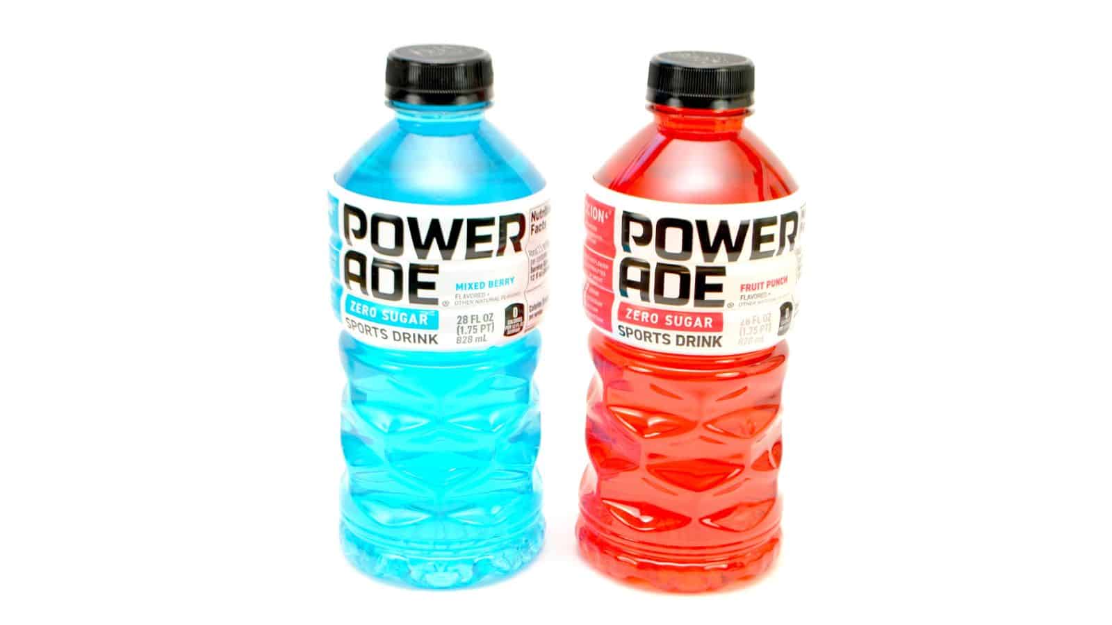 Two bottles of Powerade Zero Sugar sports drink are shown. The left bottle is blue and labeled "Mixed Berry," while the right bottle is red and labeled "Fruit Punch." Both have black caps and a white background.