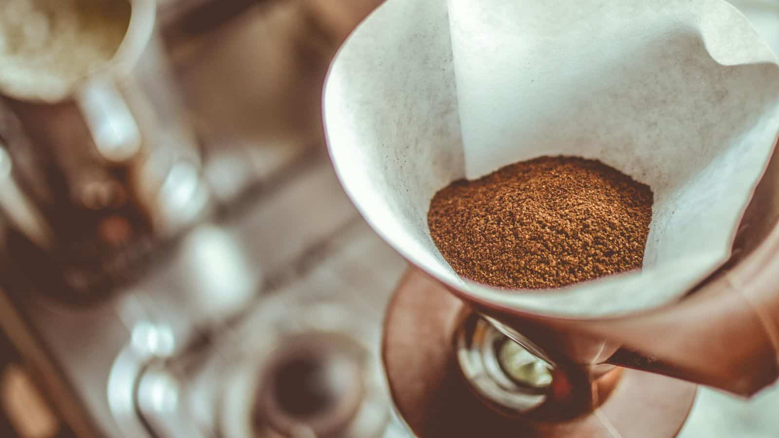 Ground coffee in a filter sits atop a pour-over coffee maker, ready for brewing—an inviting scene for anyone choosing between French press and pour-over coffee methods.