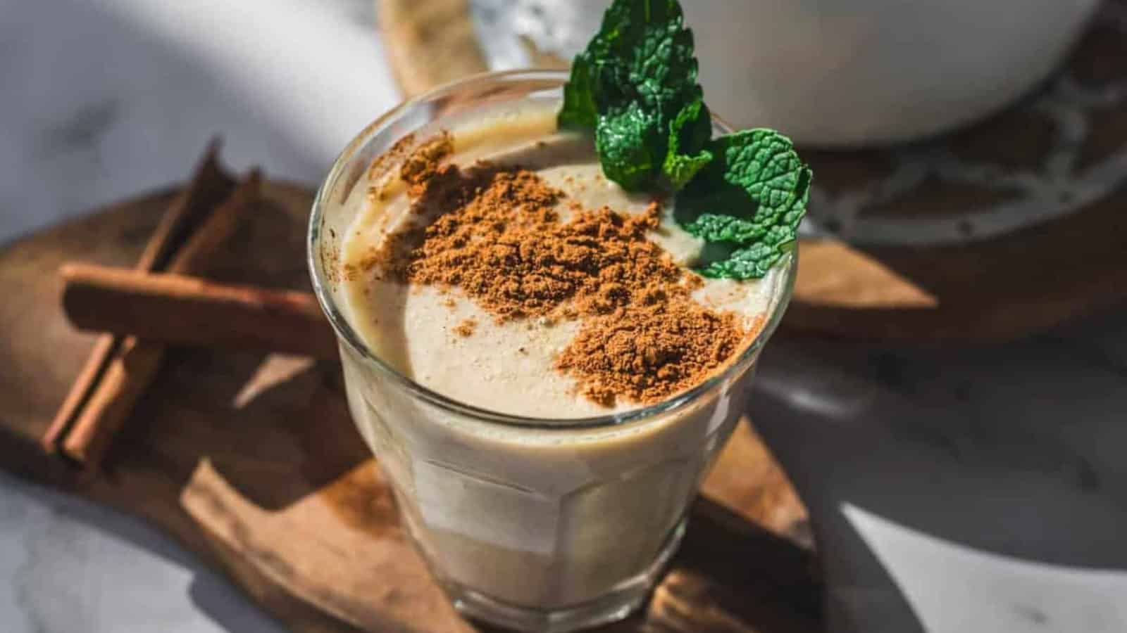 Glass of creamy cinnamon-spiced oatmeal drink with a mint garnish.
