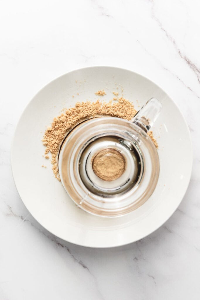 A glass jar with ground powder inside, sitting on a white plate with more powder spilled around it&mdash;perfect for your next S&rsquo;mores Latte Recipe.