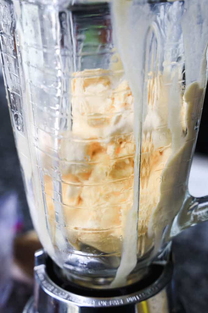 A close-up of a blender with melting ice cream inside, ready to be blended into a creamy s'mores milkshake.