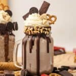 A Chocolate Freakshake in a mason jar, topped with whipped cream, pretzel, cookies, nuts, and chocolate pieces&mdash;a decadent treat for any chocolate lover.
