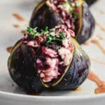 A fresh fig stuffed with goat cheese and herbs, then drizzled with honey, sits elegantly on a plate&mdash;a delightful take on goat cheese stuffed figs.