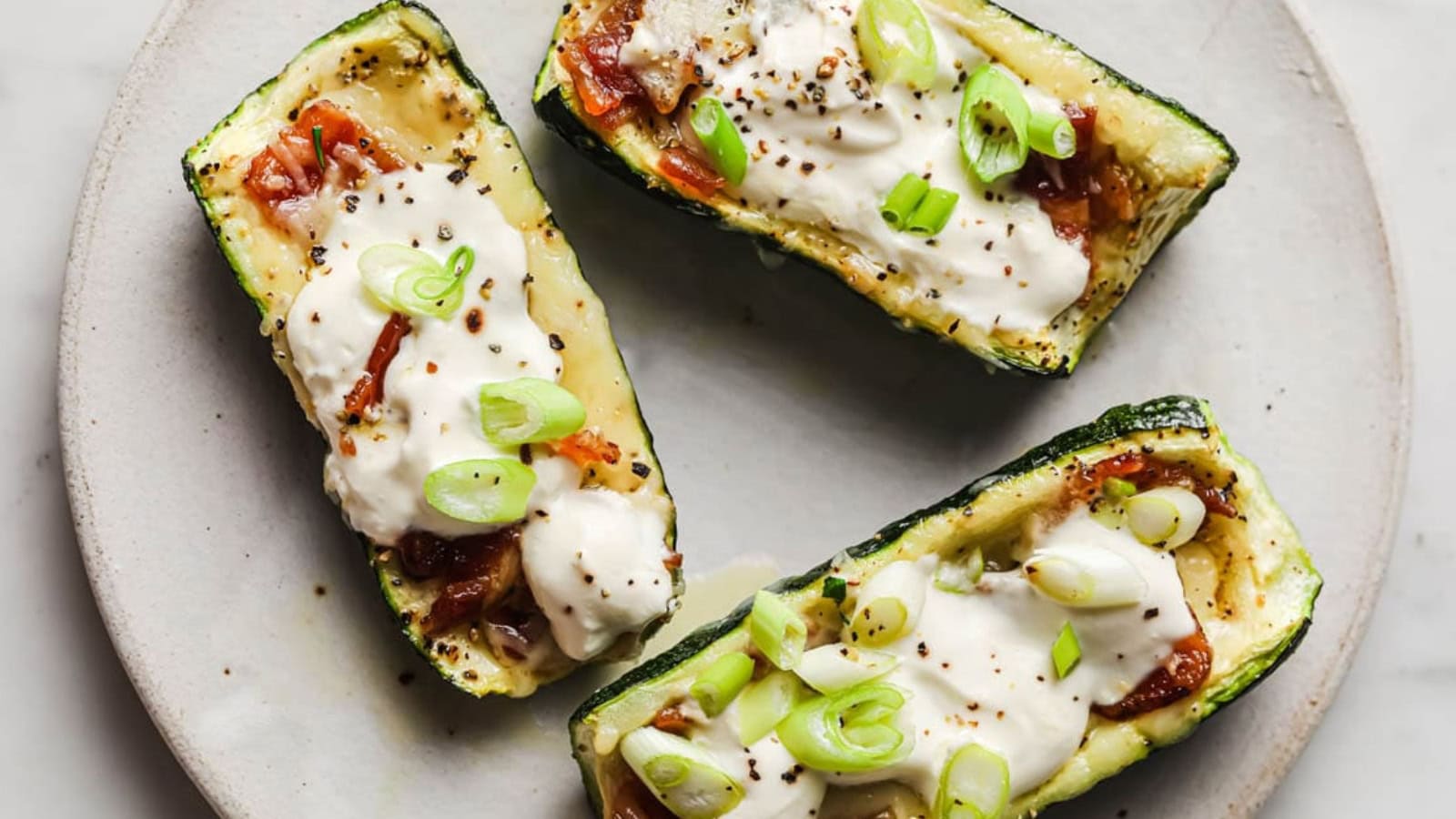 Three loaded zucchini boats on a plate.
