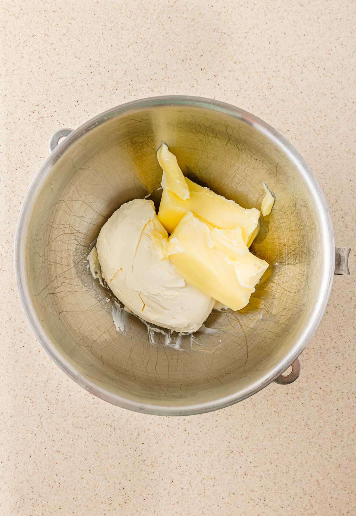 Stainless steel mixing bowl with cream cheese and butter on a light countertop, ready for making Boo Berry treats or whipping up smooth Cream Cheese Icing.