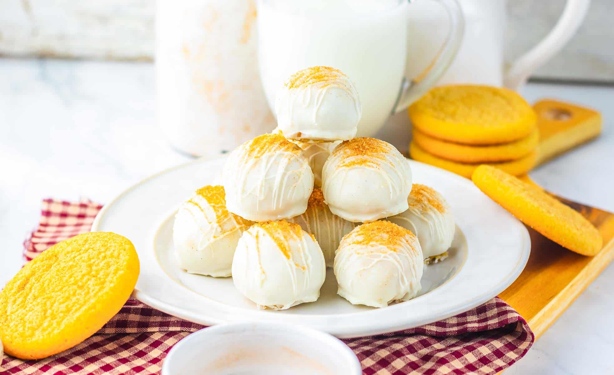 A plate of white chocolate&ndash;covered truffles topped with sprinkles, surrounded by snickerdoodle cookies and milk&mdash;perfect for anyone seeking a fun and delicious recipe.