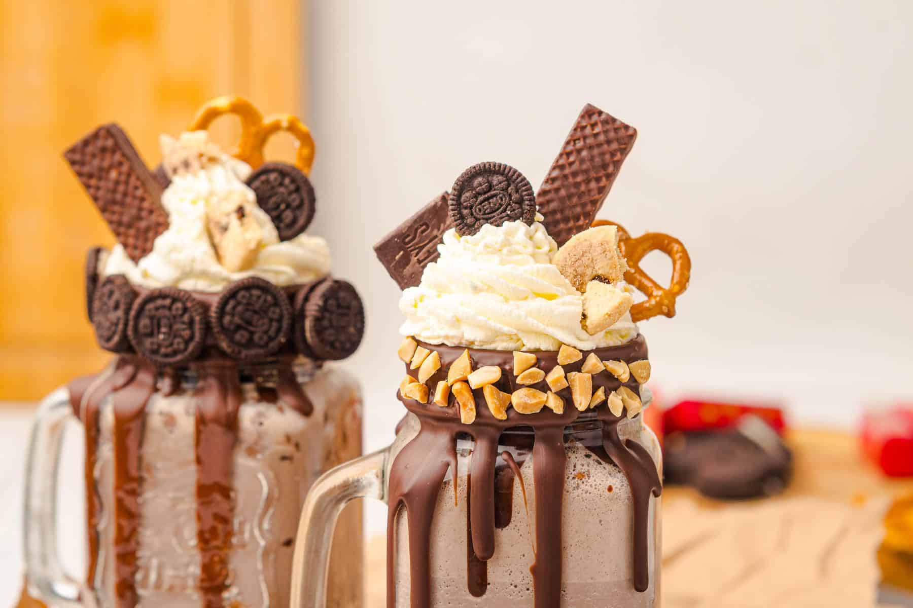 Two Chocolate Freakshakes topped with whipped cream, cookies, pretzels, wafers, and nuts in glass mugs&mdash;a decadent treat for those who love an indulgent freakshake recipe.