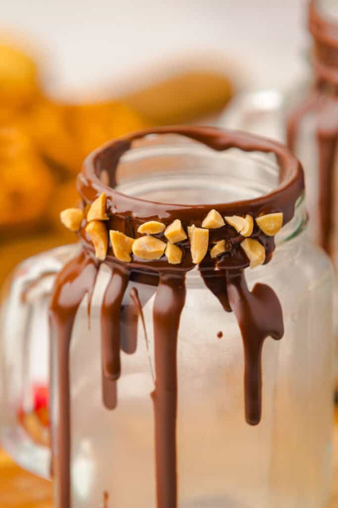 A glass mug with chocolate and chopped nuts on the rim, chocolate dripping down the sides&mdash;this indulgent Chocolate Freakshake is a must-try for any dessert lover.