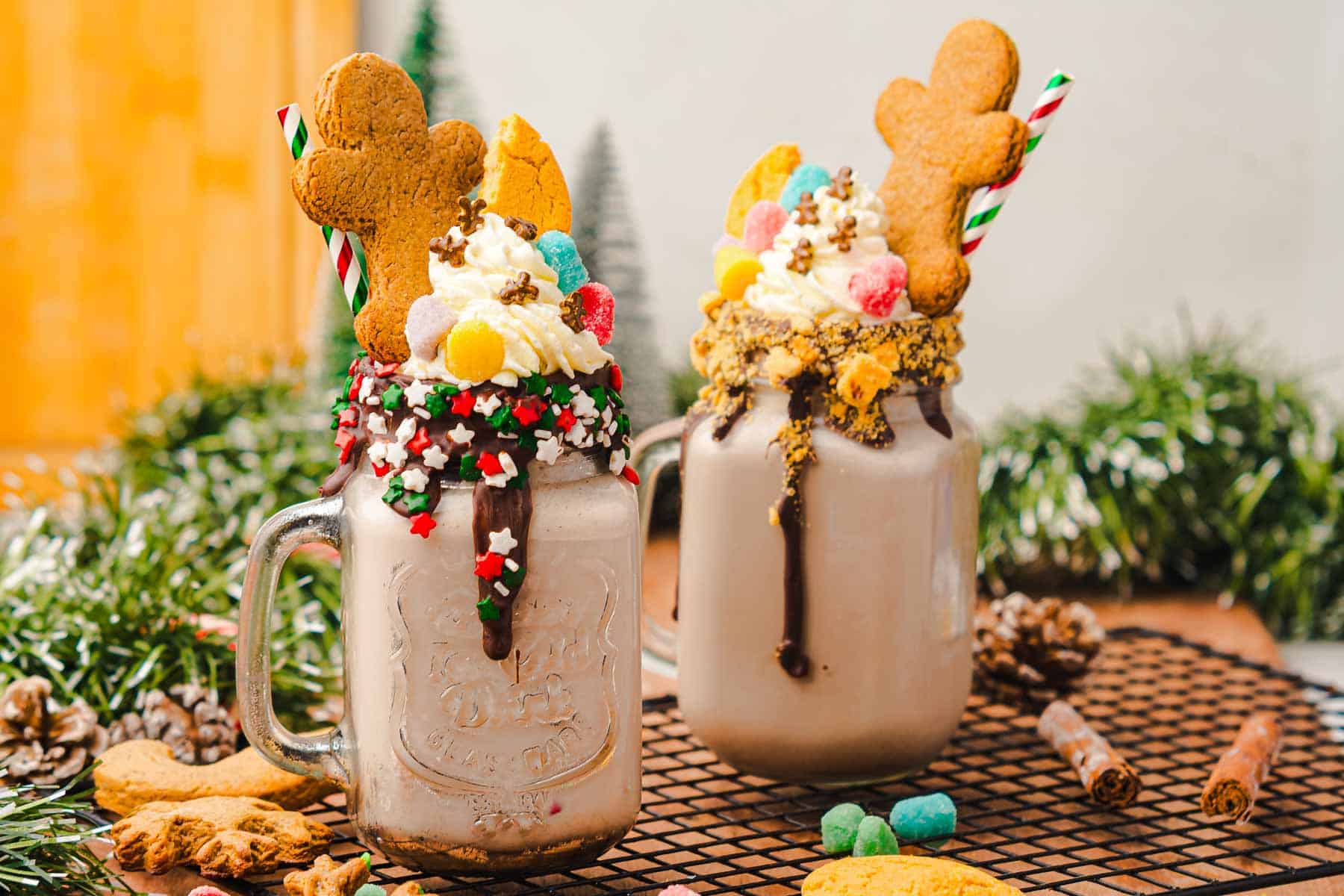 Two festive Gingerbread Freakshakes topped with gingerbread cookies, whipped cream, candy, and striped straws&mdash;a perfect Christmas recipe to delight your holiday guests.