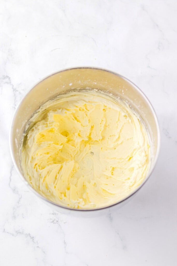 A metal mixing bowl filled with creamy, whipped butter&mdash;perfect for starting your favorite cake mix or Christmas cookies&mdash;sits on a white marble surface.