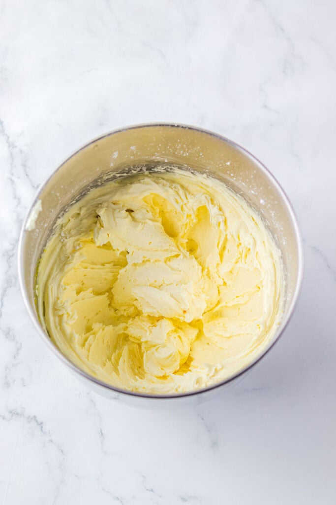 A metal bowl filled with creamy, whipped butter on a white marble surface&mdash;perfect for your favorite Christmas Cookies recipe.