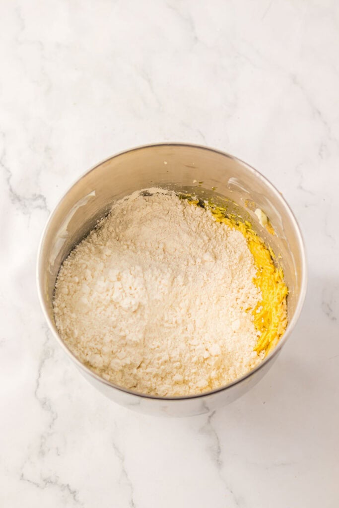 Stainless steel bowl with flour and yellow batter on a white marble surface, ready to be mixed for your favorite cake mix or Christmas cookies recipe.