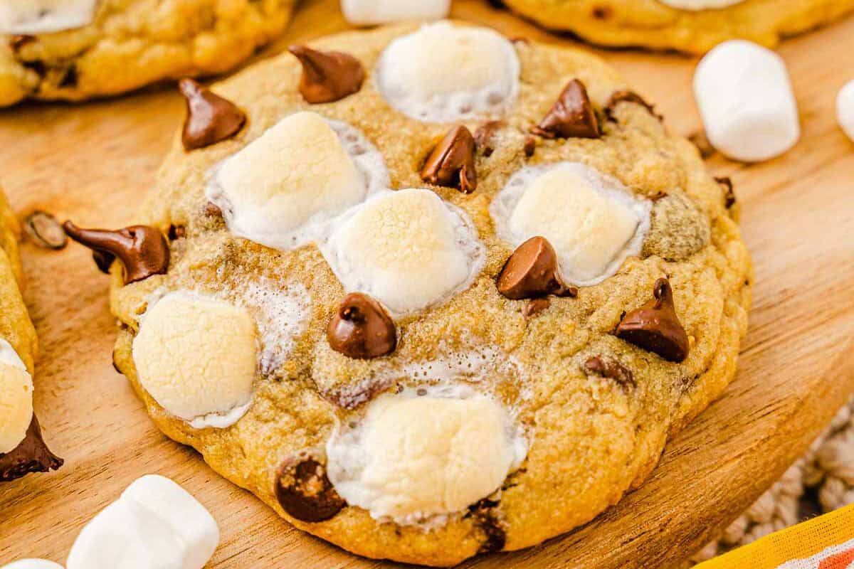 A close-up of S'mores cookies topped with toasted marshmallows on a wooden board&mdash;perfect for trying a new cookies recipe.