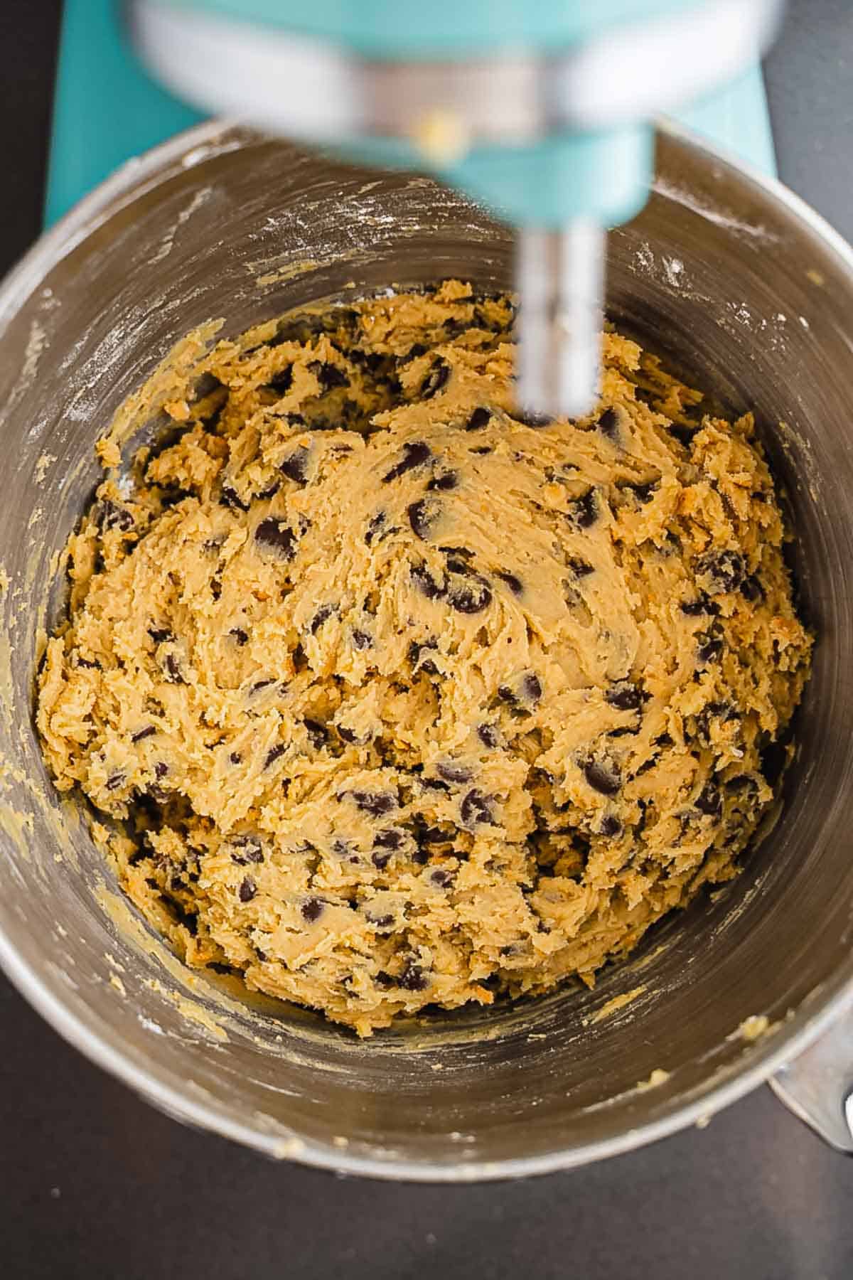 A mixing bowl filled with chocolate chip cookie dough under a stand mixer, ready to become the perfect cookies recipe or transform into irresistible S'mores cookies.