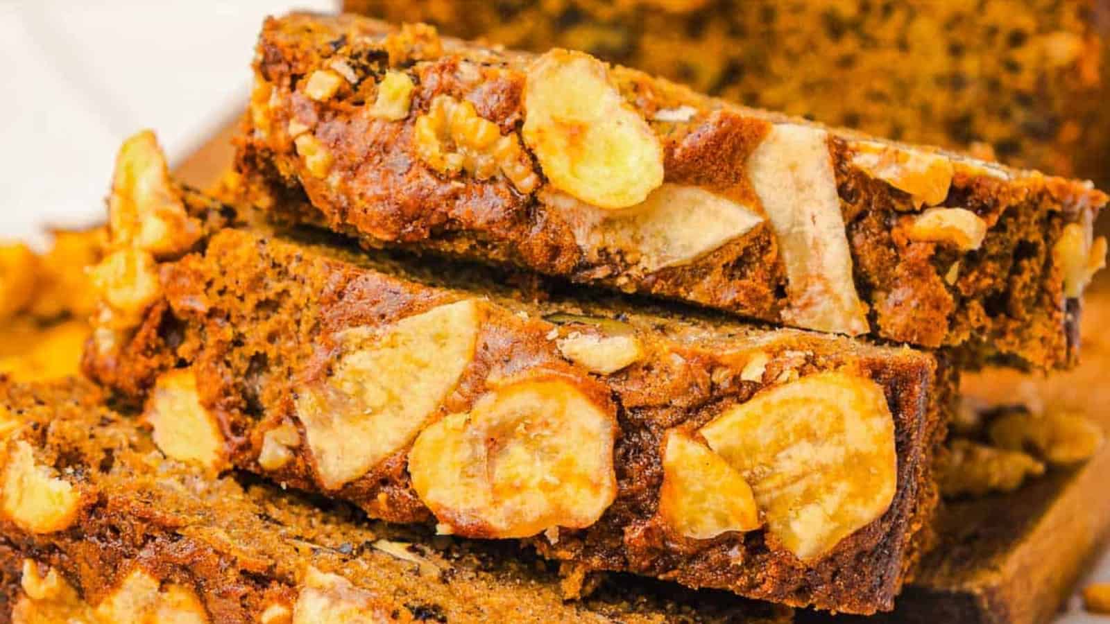 Sliced banana bread topped with banana chips and walnuts, with a Starbucks cup in the background.