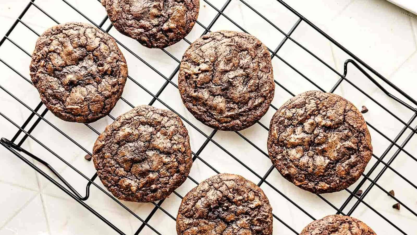 A stack of chocolate cookies, with the top cookie missing a bite, on a white surface.