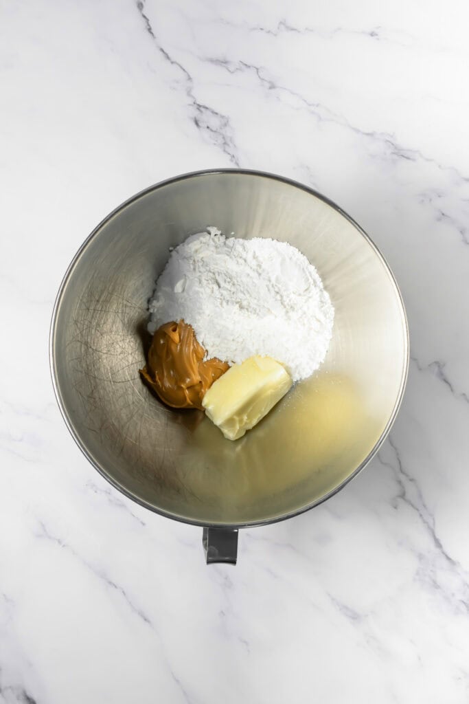 A mixing bowl with butter, peanut butter, and powdered sugar on a marble countertop&mdash;perfect for starting your Crumbl copycat peanut butter and jelly cookies.