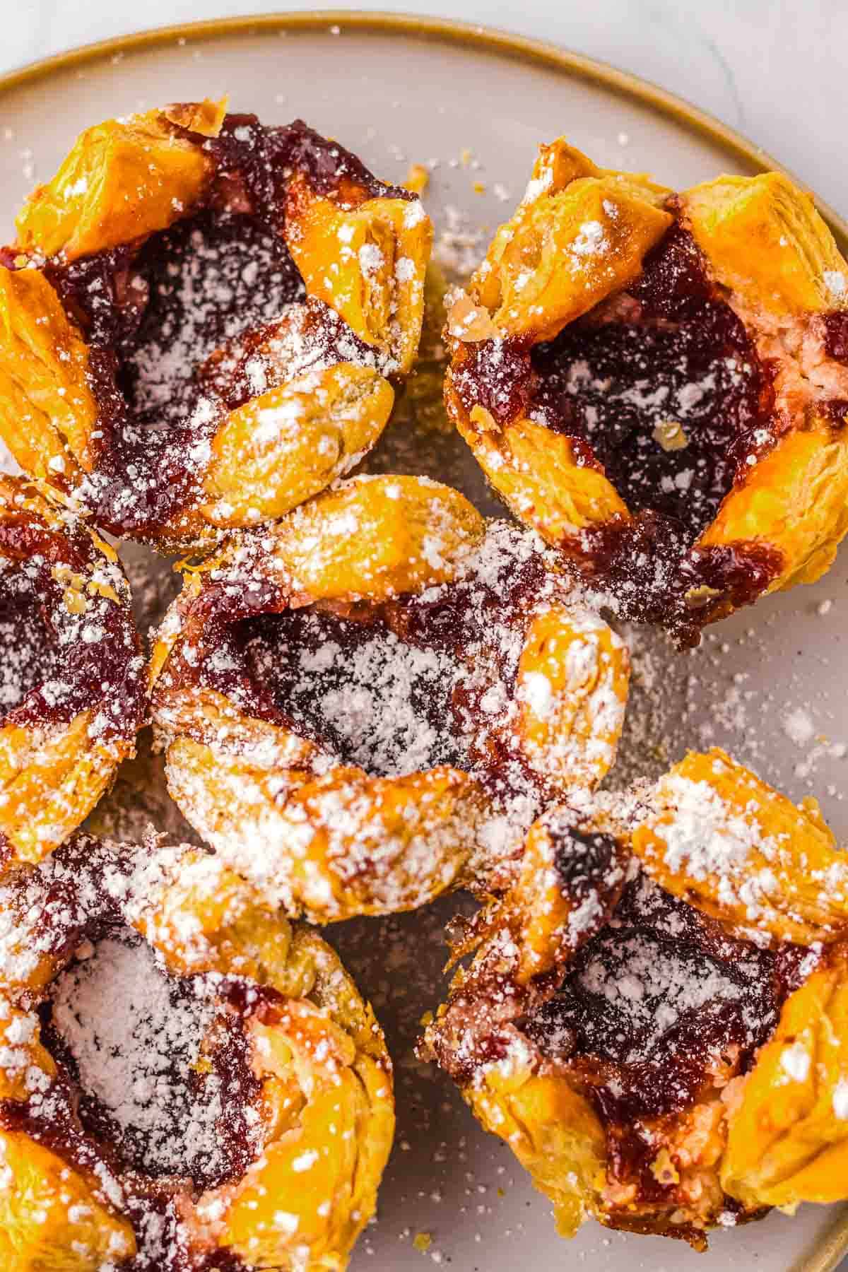 Close-up of flaky Cheese Danish pastries with a red jam center, dusted with powdered sugar, on a plate&mdash;just like your favorite Starbucks Copycat treat.