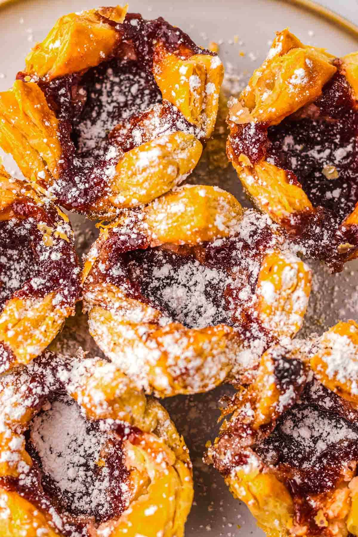 Close-up of Copycat Sugar Plum Cheese Danish tarts with fruit filling, dusted with powdered sugar on a plate&mdash;just like the ones at Starbucks.