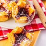 Golden puff pastry tarts filled with berry jam, topped with powdered sugar, these are the perfect copycat of Starbucks’ Sugar Plum Cheese Danish, served on a red checkered cloth.