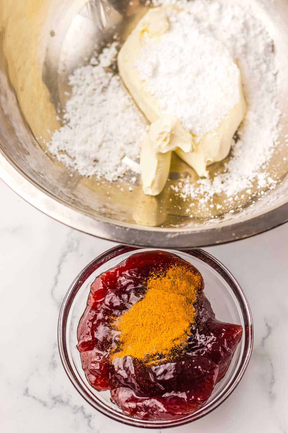 A bowl of cream cheese and powdered sugar above a bowl of cranberry sauce with orange zest on top, perfect for crafting a Starbucks Copycat Sugar Plum Cheese Danish.