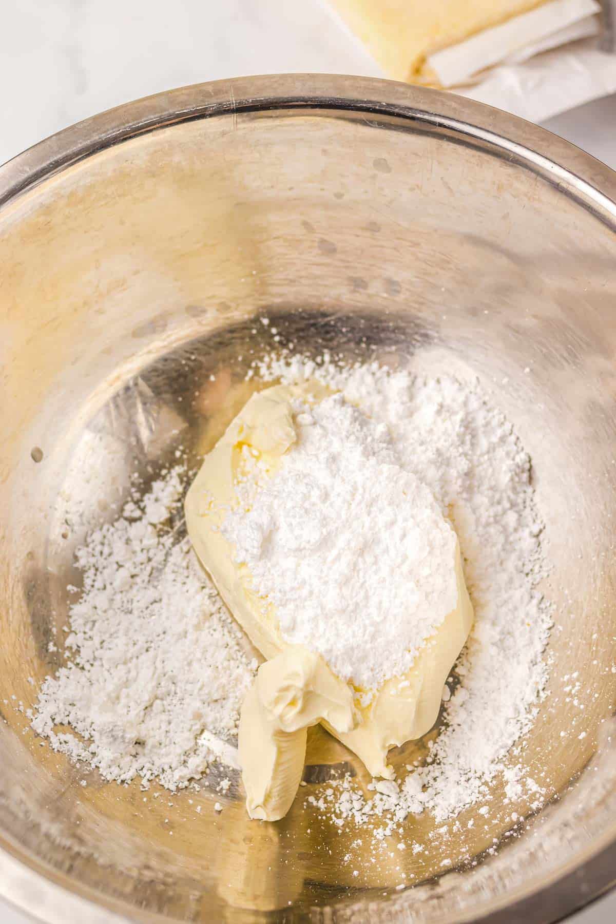 A metal bowl with butter and powdered sugar, ready to be mixed for a Starbucks Copycat Sugar Plum Cheese Danish, sits on the kitchen counter.