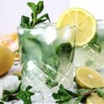 A glass of Lemon Mojito Mocktail with mint leaves, garnished with a lemon slice and fresh mint sprigs.