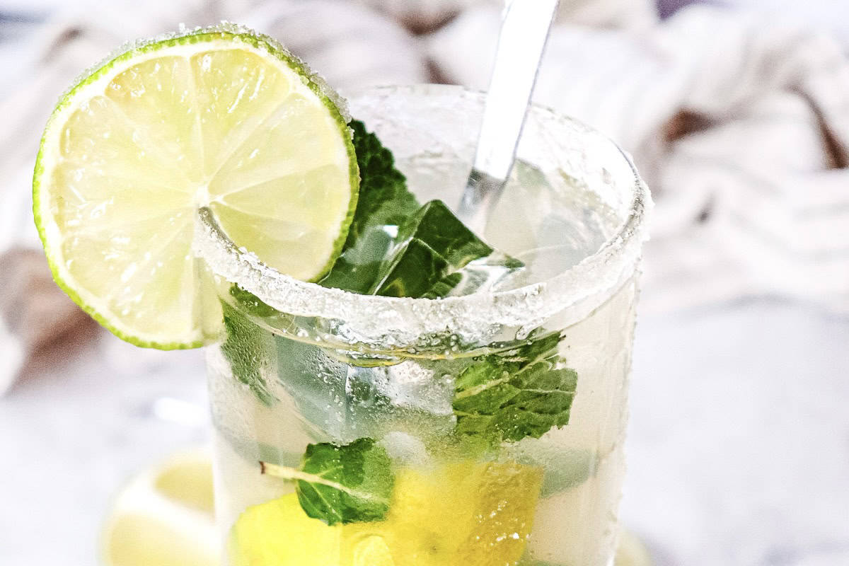A glass of Virgin Mojito with lime slice, mint leaves, and a sugar-rimmed edge.